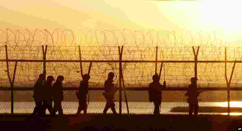 South Korean Army soldiers patrol along a barbed-wire fence near the border village of Panmunjom in Paju, South Korea, March 11, 2013.