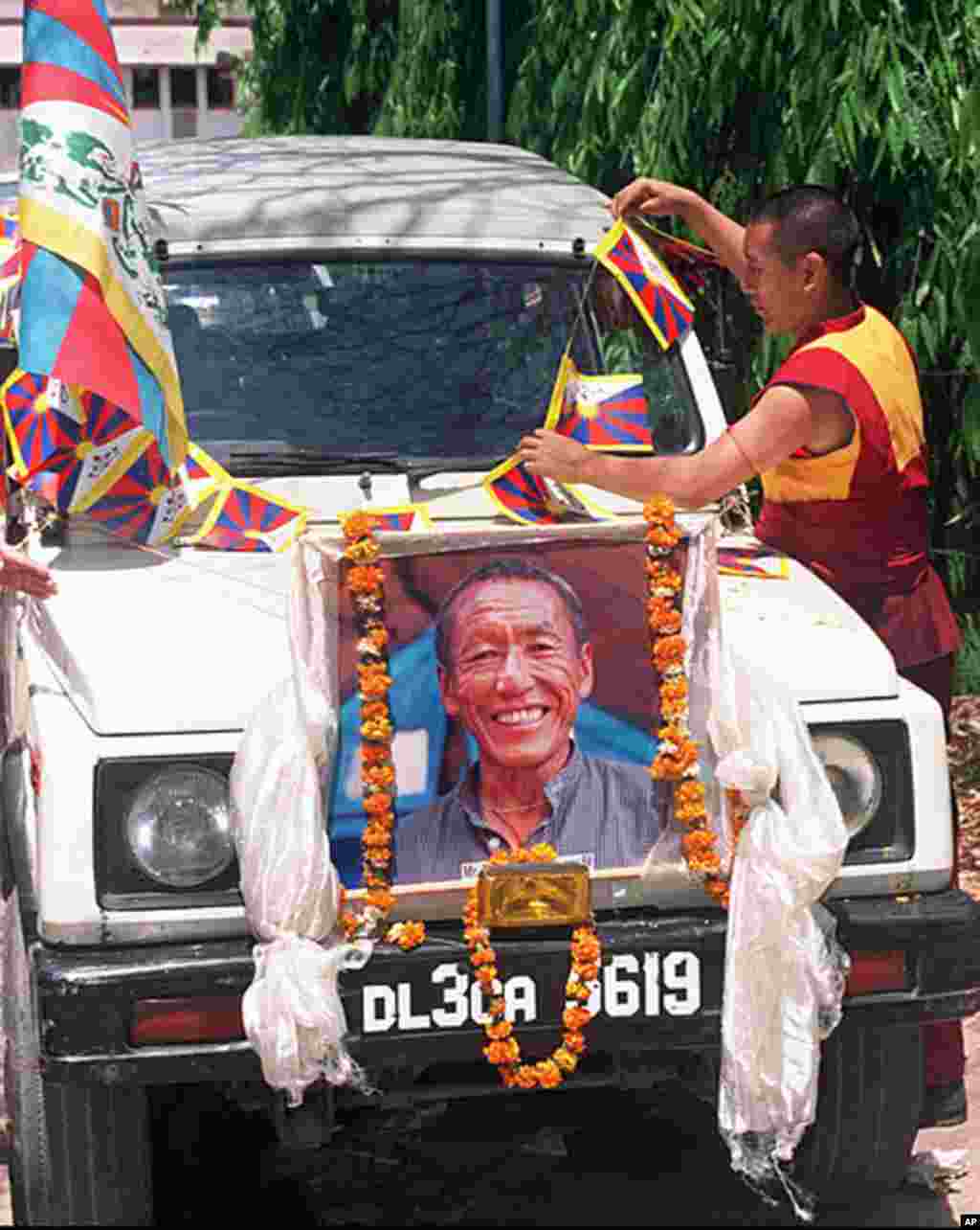 A Tibetan Buddhist monk adjusts Tibetan flags on a car above a portrait of Tibetan activist Thupten Ngodup 29 April before taking his body away in a convoy from Lady Harding hospital. Thupten died of a heart failure after setting himself alight to protes