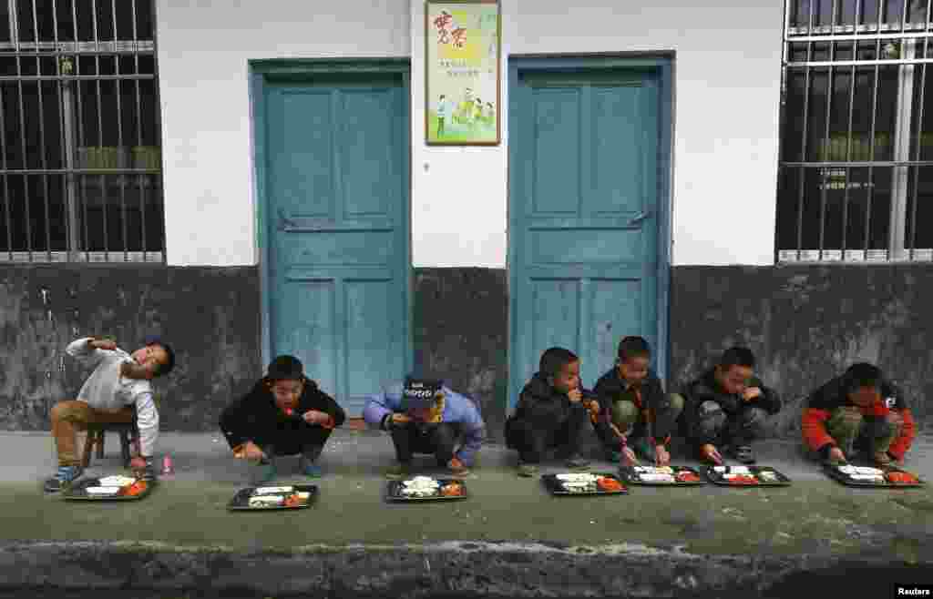 Học sinh ăn trưa bên ngoài tại một trường tiểu học ở làng Đồng Quan, huyện Lê Bình, tỉnh Quý Châu, Trung Quốc.