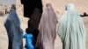 FILE - Afghan women walk through Panjwaii town, Kandahar province, Afghanistan. Women in Kabul took part in a protest Jan. 16, 2021, against a Taliban directive making wearing hijabs compulsory for women, and now several appear to have been detained.