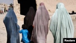 FILE - Afghan women walk through Panjwaii town, Kandahar province, Afghanistan. Women in Kabul took part in a protest Jan. 16, 2021, against a Taliban directive making wearing hijabs compulsory for women, and now several appear to have been detained.