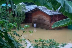 Seorang pengungsi Rohingya berjalan melewati banjir setelah hujan deras di kamp pengungsi Rohingya di Kutupalong, Bangladesh, Rabu, 28 Juli 2021. (AP)