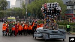 Rescue workers and volunteers that participated in rescue operations after the Sept. 19 earthquake, march behind a fist made out of safety helmets, as they lead the Day of the Dead parade on Mexico City's main Reforma Avenue, Oct. 28, 2017. 