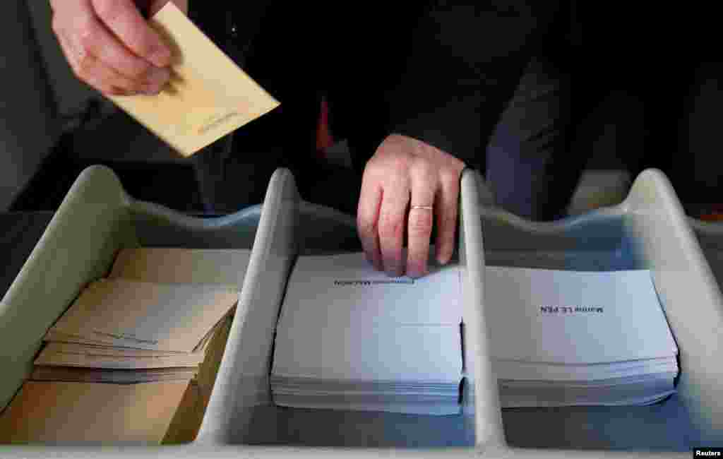 A man takes ballots to vote in the second round of 2017 French presidential election at a polling station in Marseille, May 7, 2017.