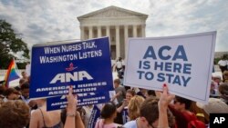 Supporters of the Affordable Care Act hold up signs as the opinion for health care is reported outside of the Supreme Court in Washington, June 25, 2015. 