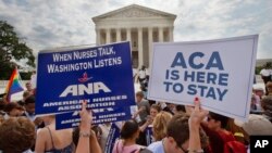 Supporters of the Affordable Care Act hold up signs as the opinion for health care is reported outside of the Supreme Court in Washington, June 25, 2015. (AP Photo/Jacquelyn Martin) 