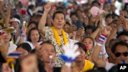 An anti-government protester raises her arm as she listens to a speech delivered by their leader Suthep Thaugsuban during a rally in Bangkok, Thailand, Saturday, May 10, 2014.