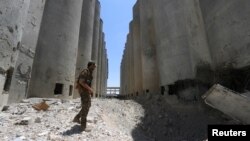 FILE - A Syria Democratic Forces (SDF) fighter walks in the silos and mills of Manbij. Recent air raids near Manbij killed at least 56 civilians. Activists are planning protests across Syria and opposition government leaders are now calling on Western countries to halt airstrikes. 