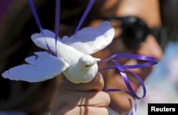 Jennifer Gordon holds a fabric dove at the base of balloons as she pays tribute to musician Prince at a makeshift memorial outside the fence of Paisley Park, his home and recording studio, in suburban Minneapolis, Minnesota, April 22, 2016.