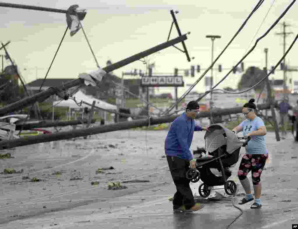 Jessica Rodgers and neighbor Ray Arellana carry a stroller over downed power lines as they head to Rodgers' mother's apartment to check on damage after a tornado tore though Jefferson City, Mo.