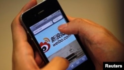 FILE - A man holds an iPhone as he visits China's Weibo microblogging site in Shanghai, May 29, 2012. Weibo has partnered with U.S.-based rating agency Nielson's to gauge marketing possibilities on the platform.