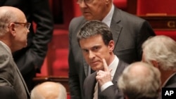 French prime minister Manuel Valls, center, leaves the France's National Assembly, in Paris, Wednesday, Feb. 10, 2016. French lawmakers voted on a divisive bill aimed at changing the constitution to introduce the possibility of revoking the citizenship of people convicted on terrorism charges in the wake of the Paris attacks.