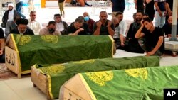 Mourners pray near the coffins of coronavirus patients who were killed in a hospital fire, during their funeral at the Imam Ali shrine in Najaf, Iraq, Sunday, April 25, 2021.