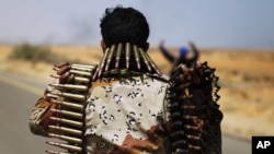 A rebel fighter carries ammunition while advancing in pursuit of forces loyal to Maammar Gadhafi some 120 km (75 miles) east of Sirt in eastern Libya, March 28, 2011