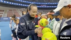 Tenista chino Peng Shuai firma pelotas de tenis de gran tamaño en la ceremonia de apertura de la Fila Kids Junior Tennis Challenger Final en Beijing, China, el 21 de noviembre de 2021, en esta captura de pantalla obtenida de un video de las redes sociales. TWITTER @QINGQINGPARIS 
