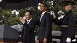 U.S. President Barack Obama and South Korean President Lee Myung-bak (L) are sheltered from the rain by U.S. military personnel (R) holding umbrellas on the South Lawn of the White House in Washington, October 13, 2011.