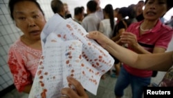 FILE - A woman shows petitioning papers bearing petitioners' thumbprints to Reuters journalists near the State Bureau For Petitions and Visits, which handles applications from petitioners from all over China.