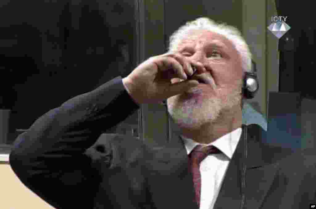 In this photo provided by the ICTY, former Bosnian Croat military commander Slobodan Praljak (C) appeared to dring poison seconds during a Yugoslav War Crimes Tribunal in The Hague, Netherlands, after judges upheld his 20-year prison sentence for involvement in a campaign to drive Muslims out of a would-be Bosnian Croat ministate in Bosnia in the early 1990s.