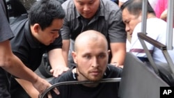In this photo released by the Crime Suppression Division of the Thailand Police, Sergey Medvedev, 31 (C) is arrested outside an apartment for his role in an international identity theft ring that sold stolen credit card information on the dark web, leading to losses of over $530 million, Feb. 2, 2018.