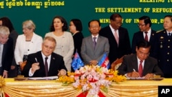 Australian Immigration Minister Scott Morrison, front left, signs a document together with Cambodian Interior Minister Sar Kheng, front right, during a signing ceremony of a controversial deal on resettlement of refugees inside the Interior Ministry in Ph
