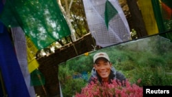 A portrait of Ankaji Sherpa, who lost his life in an avalanche at Mount Everest last Friday, is seen near a prayer flag during the cremation ceremony of Nepali Sherpa climbers in Kathmandu, April 21, 2014.