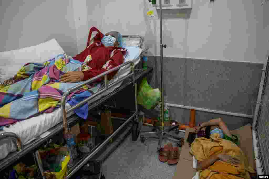 A COVID-19 patient rests while his daughter and watcher sleeps on the floor of the COVID-19 emergency room at the government National Kidney and Transplant Institute in Quezon City, Metro Manila, Philippines.