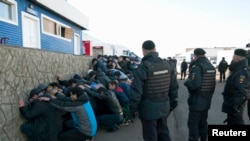 Russian police detain migrant workers during a raid on October 14, 2013. 