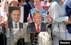 FILE - People hold images of Polish President Andrzej Duda and U.S. President Donald Trump during Trump's public speech at Krasinski Square, in Warsaw, Poland, July 6, 2017.