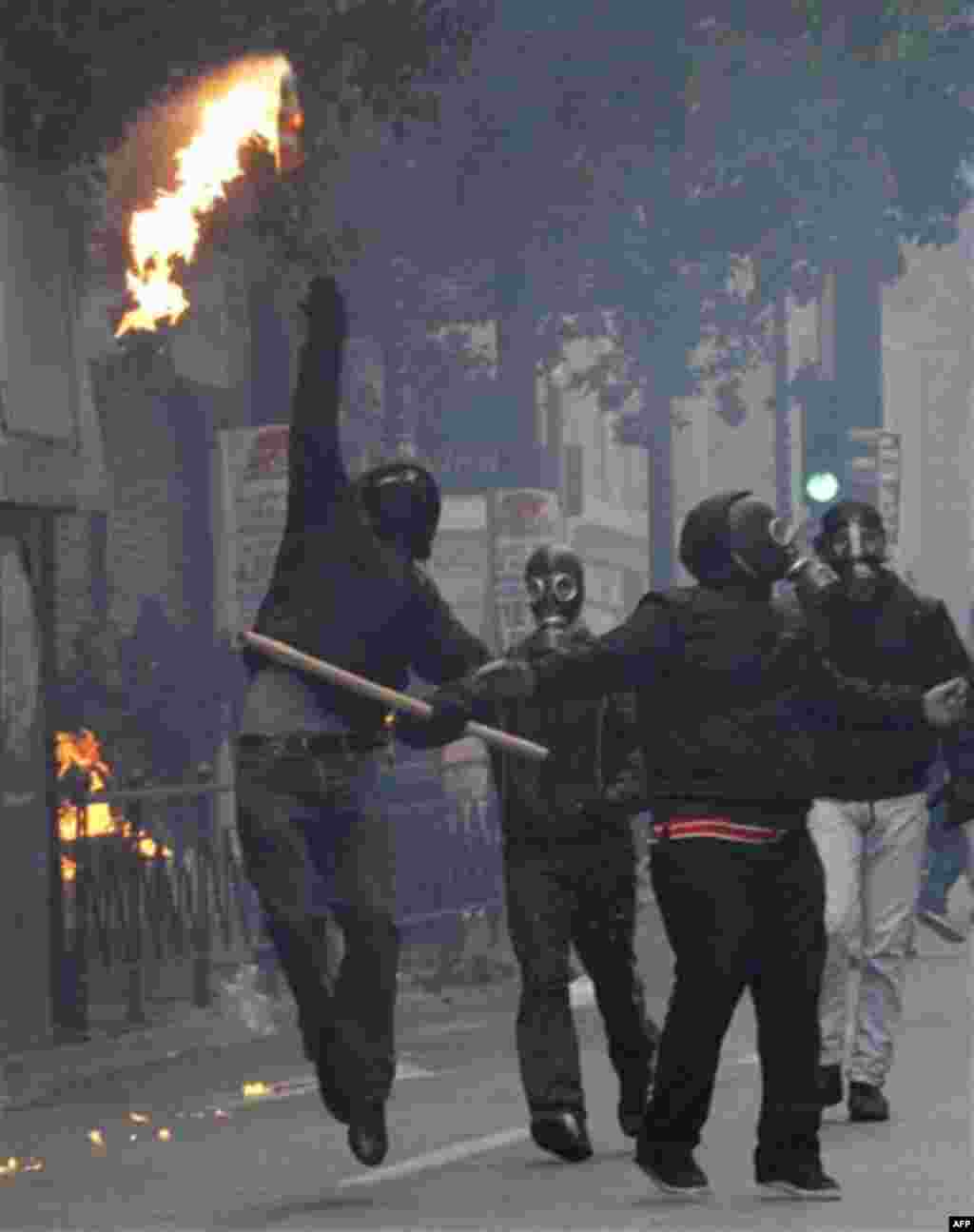 A protester throws a petrol bomb at riot police during clashes in Athens, Wednesday, Dec. 15, 2010. Hundreds of protesters clashed with riot police across central Athens Wednesday, smashing cars and hurling gasoline bombs during a massive labor protest ag