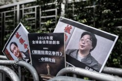 香港抗議者在北京駐香港機構中聯辦前手舉銅鑼灣書店失踪老闆桂民海的照片。（2016年1月19日）
