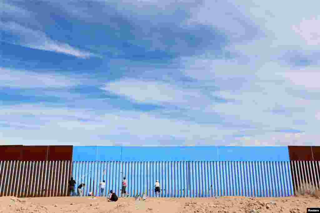 Volunteers paint the border fence between the United States and Mexico to give the illusion of transparency during the &quot;Borrando la Frontera&quot; (Erasing the Border) Art Project in Mexicali, Mexico April 9, 2016.