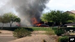 Dua rumah terbakar akibat jatuhnya pesawat jet Herrier milik militer AS di daerah perumahan Imperial, California, Rabu (4/6). (AP Photo/Jose Santos).