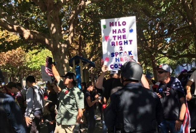 FILE - Berkeley police officers stand guard for planned speech by Milo Yiannopoulos in Berkeley, Calif., Sept. 24, 2017. Milo Yiannopoulos was whisked away in a car after a brief appearance at the school that drew a few dozen supporters and a slightly larger crowd of protesters.
