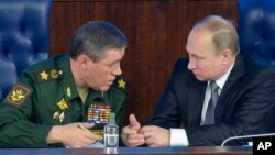 FILE - Russian President Vladimir Putin, right, speaks with the Chief of the General Staff of the Russian Armed Forces Valery Gerasimov at a meeting with top military officials in Moscow, Russia, Dec. 11, 2015. Putin is said to be considering the deployment of ground troops in Syria.
