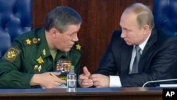 Russian President Vladimir Putin, right, speaks with Chief of the General Staff of the Russian Armed Forces Valery Gerasimov at a meeting with top military officials in the National Defense Control Center in Moscow, Russia, Dec. 11, 2015. 