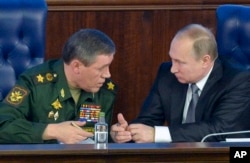 FILE - Russian President Vladimir Putin, right, speaks with Chief of the General Staff of the Russian Armed Forces Valery Gerasimov at a meeting with top military officials in the National Defense Control Center in Moscow, Russia, Dec. 11, 2015.