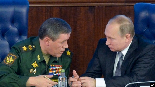 FILE - Russian President Vladimir Putin, right, speaks with Chief of the General Staff of the Russian Armed Forces Valery Gerasimov at a meeting with top military officials in the National Defense Control Center in Moscow, Russia.