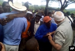 Farmers Robert Smart, right, and his son, Darryn, are welcomed back to their farm, Lesbury, by workers and community members, Dec. 21, 2017 in Tandi, Zimbabwe.