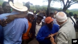 Farmers Robert Smart, right, and his son, Darryn, are welcomed back to their farm, Lesbury, by workers and community members, Dec. 21, 2017 in Tandi, Zimbabwe.