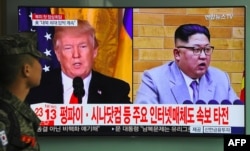 ທະຫານເກົາຫຼີໃຕ້ ຜູ້ນຶ່ງຍ່າງຜ່ານໜ້າຈໍໂທລະພາບ ທີ່ເຫັນປະນາທິບໍດີສະຫະລັດ ທ່ານດໍໂນລ ທຣຳ (Donald Trump) (ຊ້າຍ) ແລະຜູ້ນຳເກົາຫຼີເໜືອ ກິມ ຈົງ ອຶນ (Kim Jong Un) ທີ່ີສະຖານີລົດໄຟ ທີ່ໂຊໃນ 9 ມີນາ 2018.