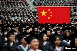 FILE - Students attend a graduation ceremony at Fudan University in Shanghai, June 23, 2017.