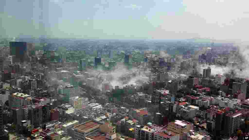 In this photo provided by Francisco Caballero Gout, shot through a window of the iconic Torre Latina, dust rises over down town Mexico City during a 7.1 earthquake, Sept. 19, 2017. 