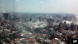 In this photo provided by Francisco Caballero Gout, shot through a window of the iconic Torre Latina, dust rises over down town Mexico City during a 7.1 earthquake, Sept. 19, 2017.
