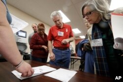 FILE - Observers look over test results as a statewide presidential election recount begins Dec. 1, 2016, in Milwaukee.