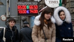 The Russian ruble fell sharply on opening on Monday, following a weekend of violence in eastern Ukraine and threats of further Western sanctions against Russia. People walk past a board showing currency exchange rates in Moscow, Jan. 26, 2015. 