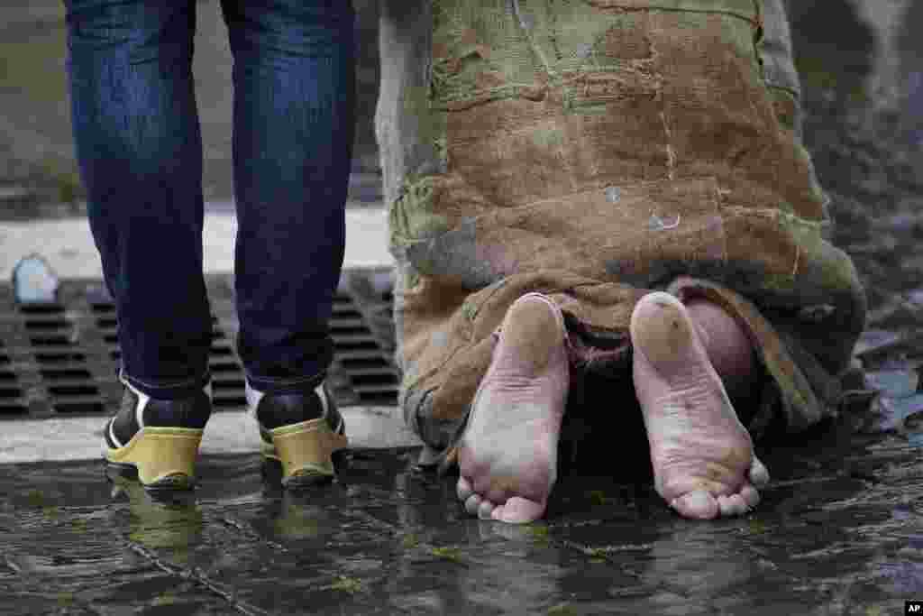 A pilgrim kneels in St. Peter's Square during a mass at St. Peter's Basilica attended by cardinals before sequestering themselves in the Sistine Chapel to elect the next pope at the Vatican, March 12, 2013.