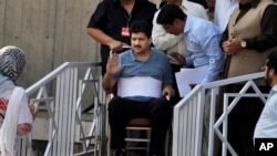 FILE - Pakistani journalist Hamid Mir, who was injured in an attack by unknown assailants on April 19, 2014, waves as he leaves the Supreme Court in Islamabad, Pakistan, May 19, 2014. He appeared at the court as part of an inquiry into the attack.