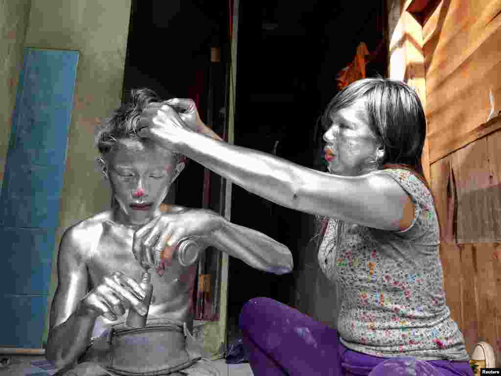 Puryanti, a 29-year-old woman, and her 15-year-old nephew Raffi, cover themselves in silver paint to become &#39;manusia silver&#39; (silver people), as part of their way to make a living, in Depok, on the outskirts of Jakarta, Indonesia.