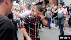 A man holds his face after being hit with pepper spray during a demonstration outside a campaign event for Republican presidential candidate Donald Trump in San Diego, Calif., May 27, 2016. 