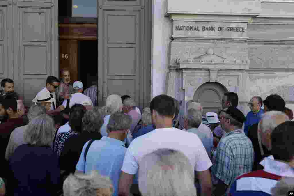 The first customers, most of them pensioners, stand in a queue to enter a branch at National Bank of Greece headquarters in Athens, July 20, 2015.